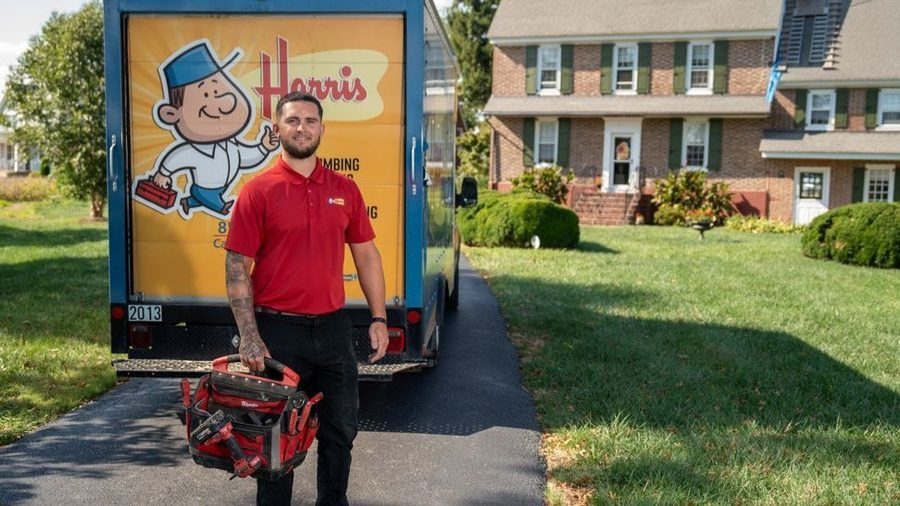 Harris electrician holding tool bag outside of van.