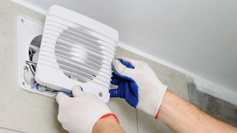 Gloved hands installing exhaust fan.