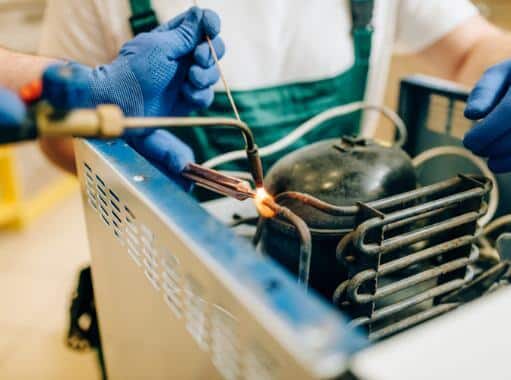 A technician in Delaware soldering a pipe of a cooling system | Delaware Cooling Services | Call Harris Now