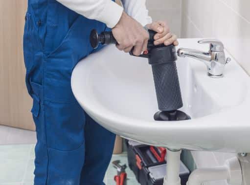 A plumber in Delaware clearing drain of a lavatory | Delaware Plumbing Services | Call Harris Now