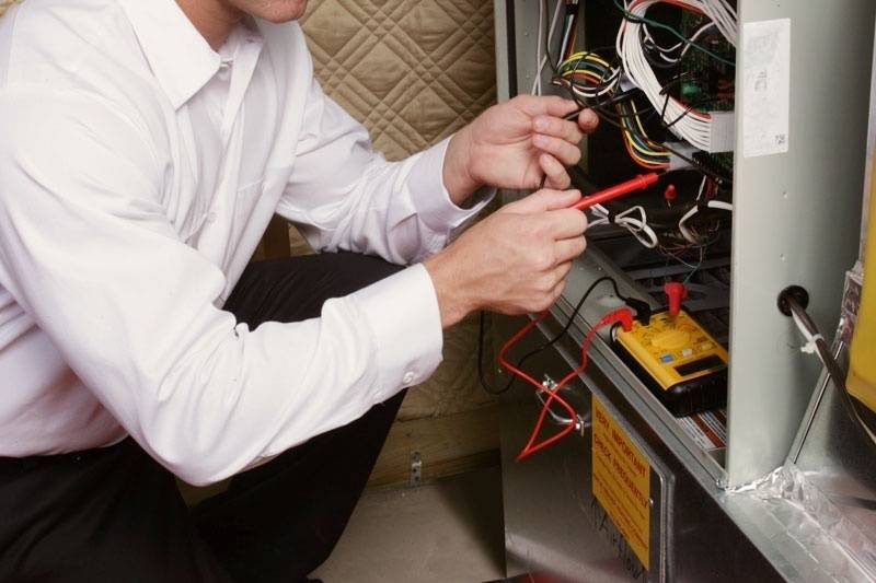 Male technician making repairs on a furnace.