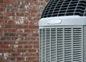 Close-up of a new heat pump beside a brick home.