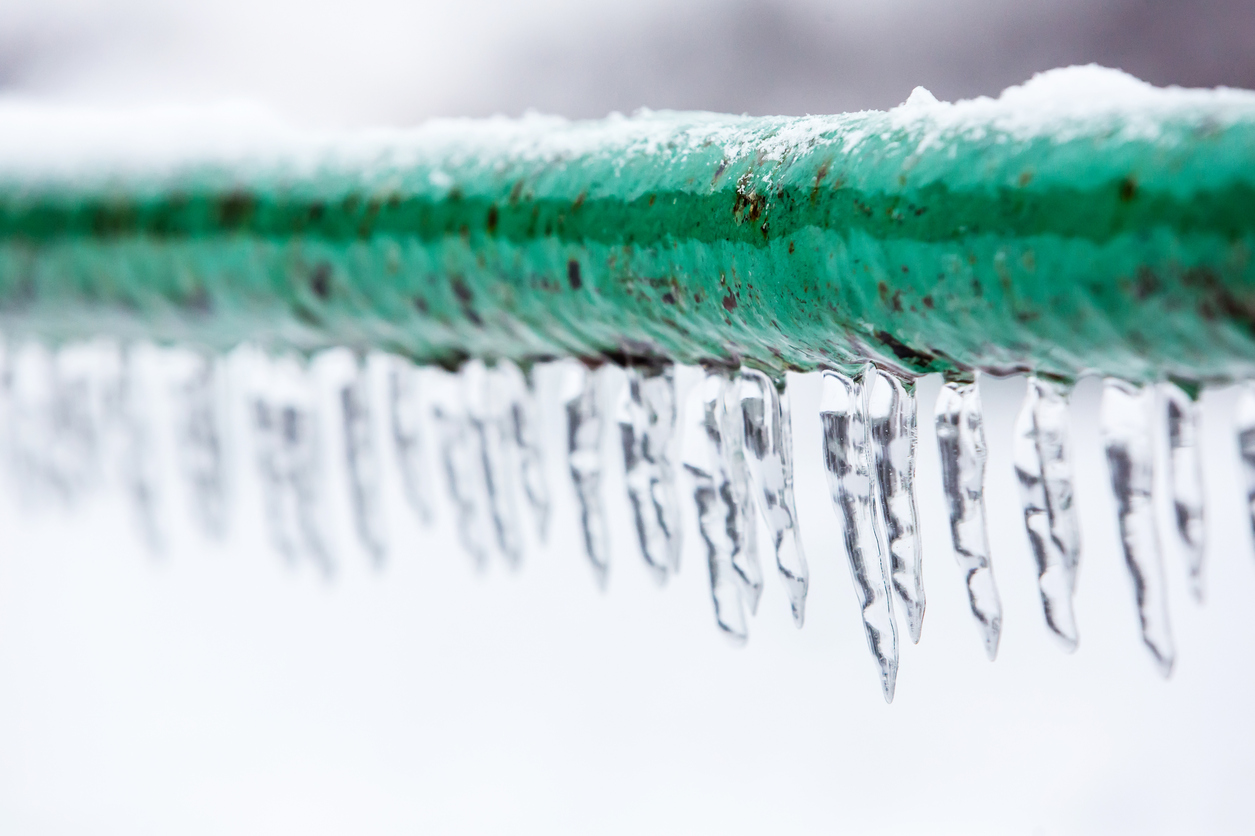 Close-up of a frozen pipes; icicles hanging from pipe.