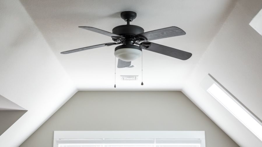 Ceiling fan installed in ceiling of pitched room.