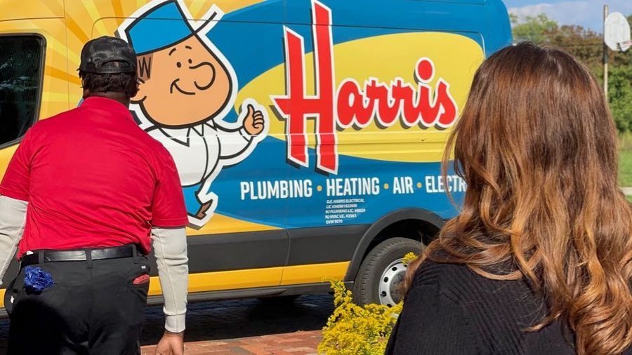 Harris Plumbing, Heating, Air & Electric technician arriving at a customer's home for professional plumbing repairs and home service while the homeowner greets them outside.
