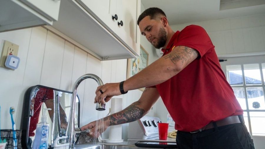Plumber testing faucet after installing water treatment solution.