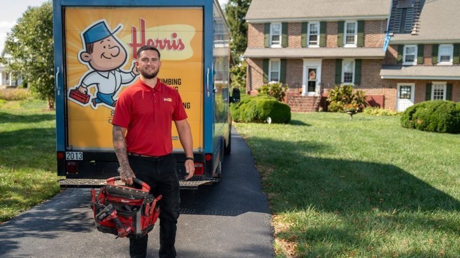 Harris technician holding tool box in front of Harris truck.